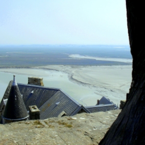 I paused as we climbed the winding streets to the top of Mont Saint-Michel and took this photo past the gnarled tree, over the rooftops and onto the horizon. The tiny people exploring the marshes come up clearly when the zoom is applied. https://amaviedecoeurentier.wordpress.com/2015/01/31/mont-saint-michel/