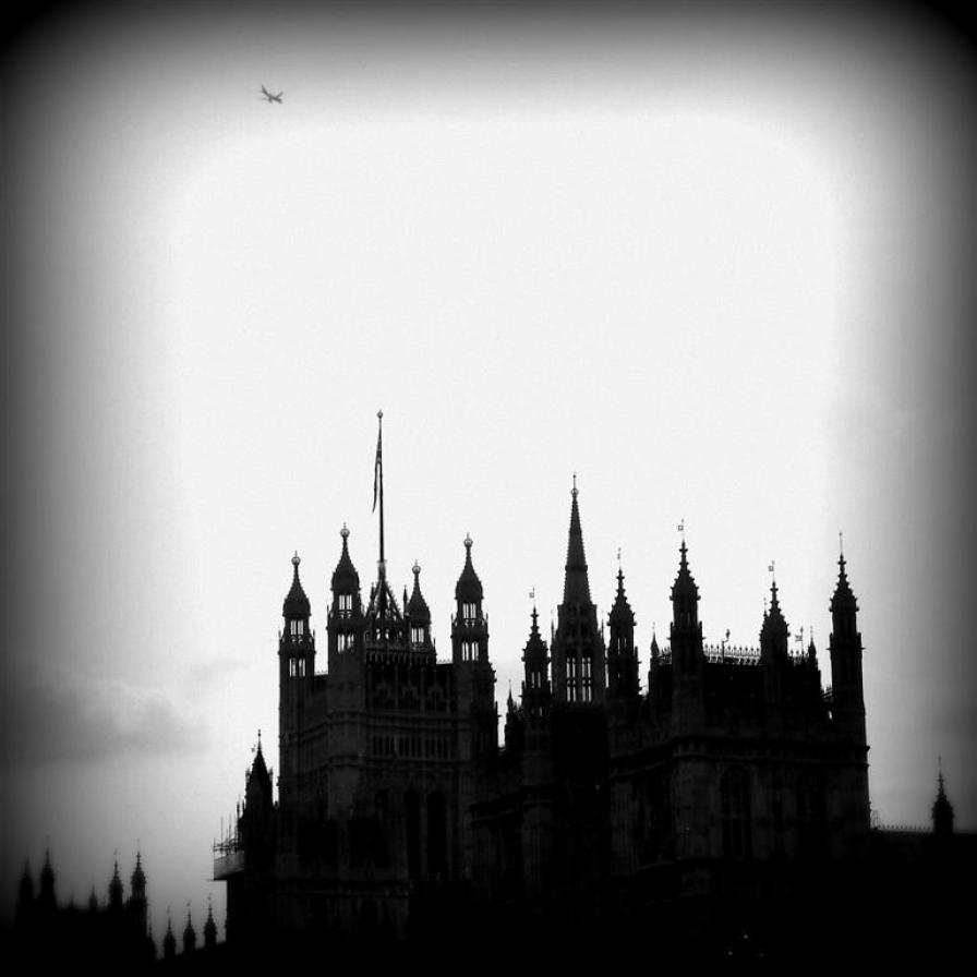 A plane flies above the Gothic spires of the British House of Parliament